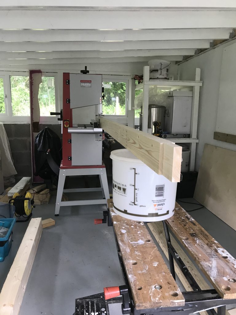 Trestle stretcher balanced on bucket to align with band saw table in distance