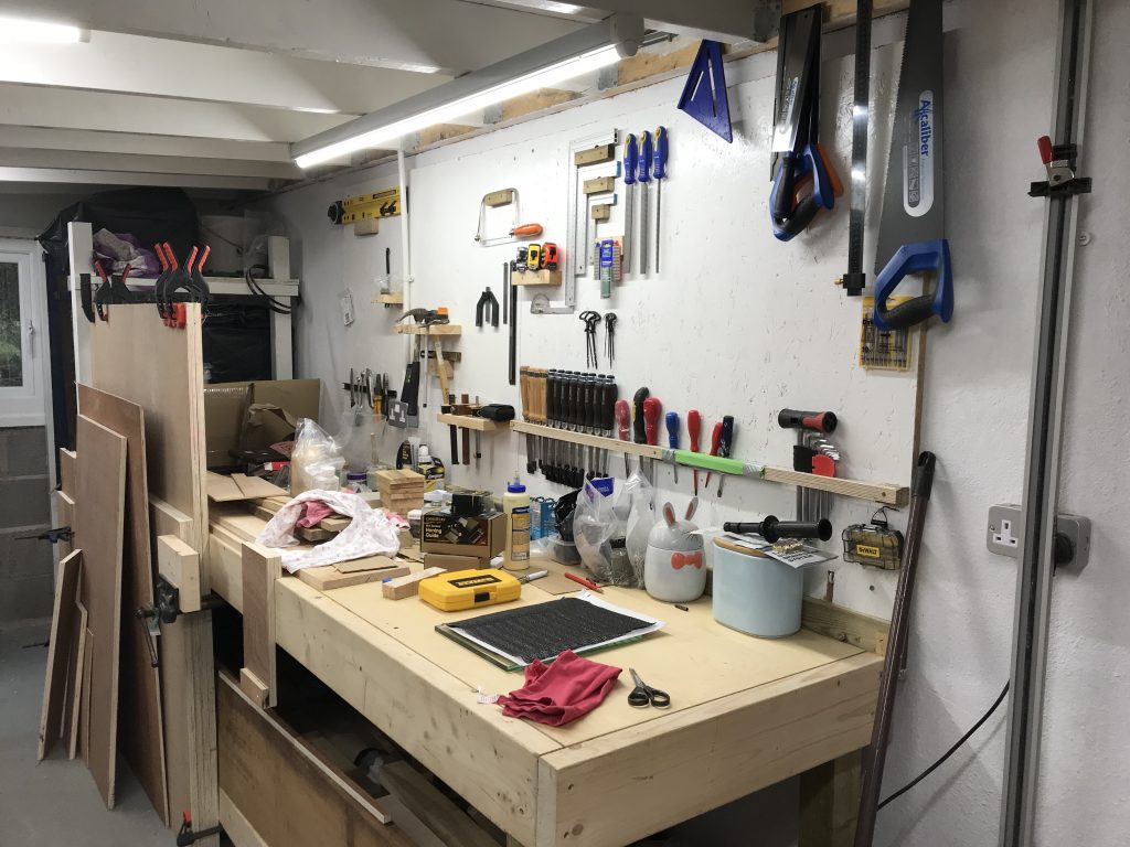 Workbench covered in odds and sods with tool board behind
