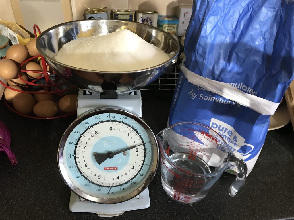 A scales with sugar and a measuring jug of water.
