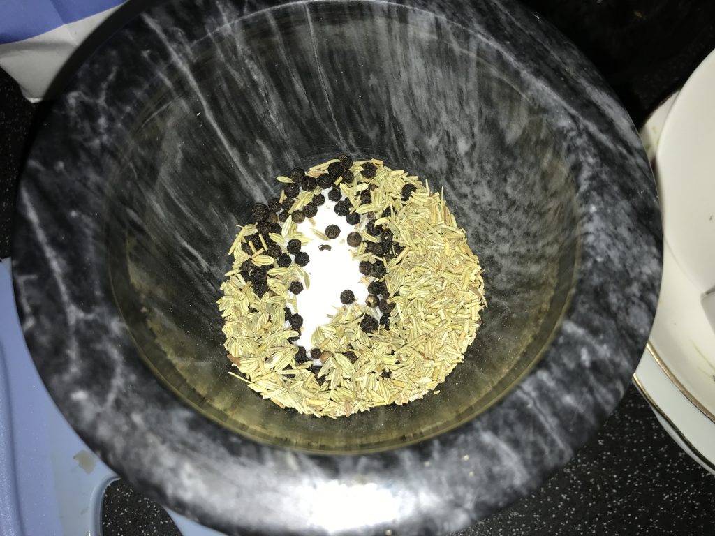 A pestle and mortar with salt, pepper, fennel and cumin seeds waiting to be bashed.