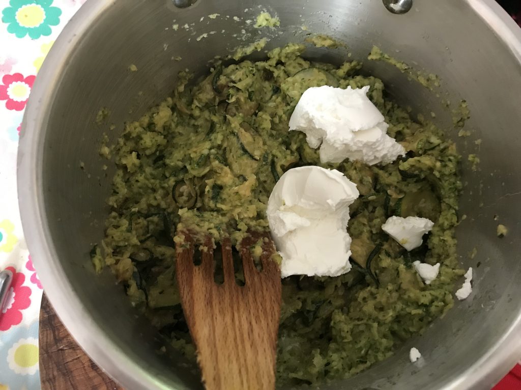 A saucepan of mashed courgette and some soft goats cheese waiting to be stirred in.
