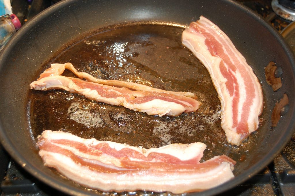 Fresh cured bacon slices in a pan about to fry.