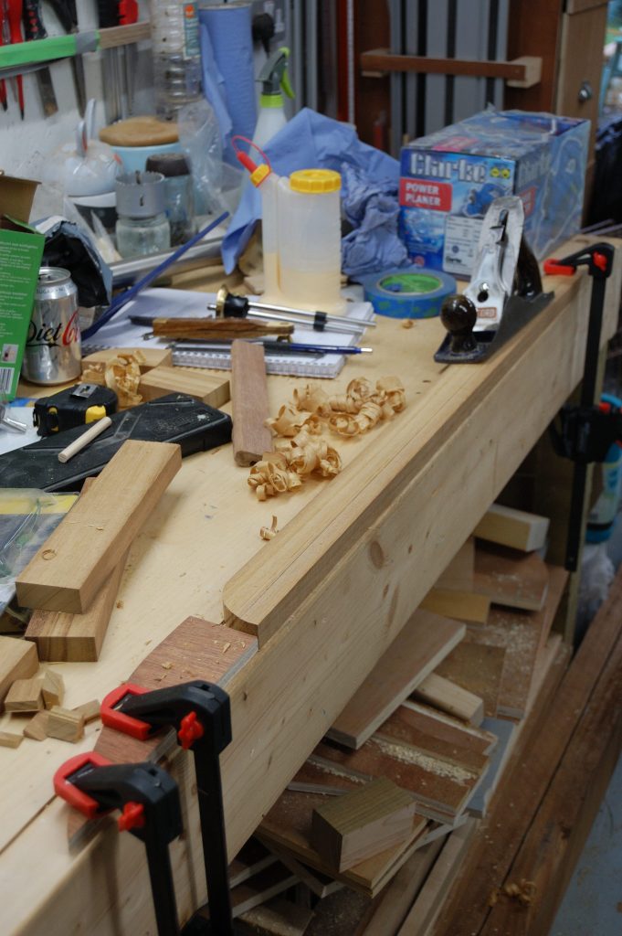 A length of Iroko on teh workbench being hand planed.