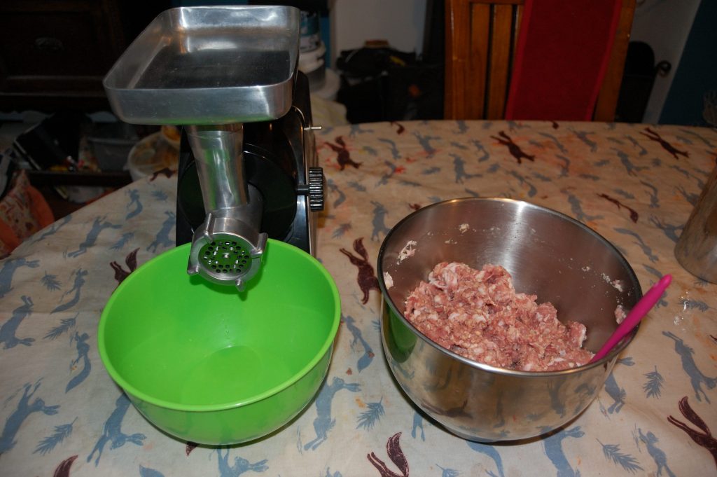 An electric sausage mixer and a bowl of mixed ingredients.