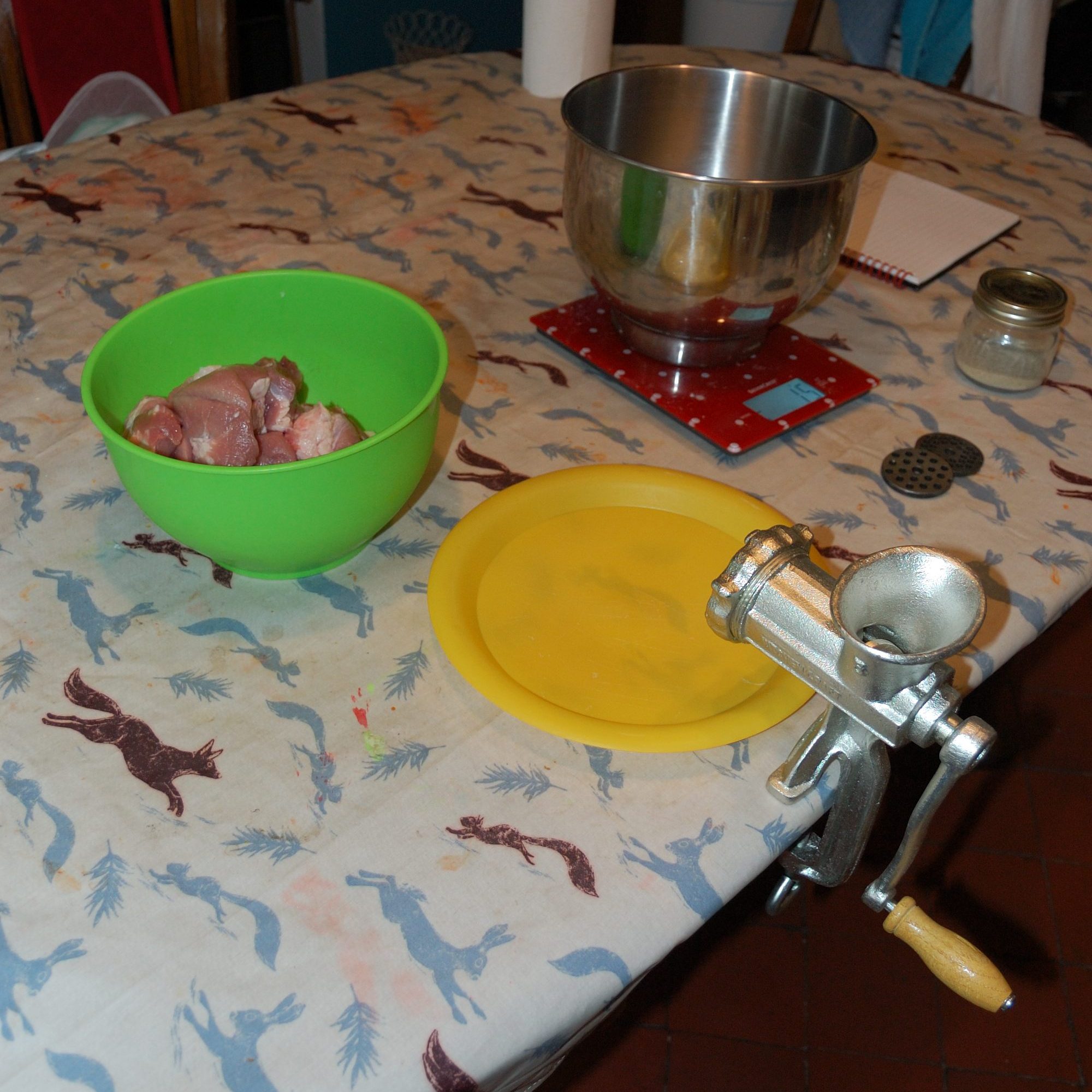 A table with a manual micer and a bowl full of pork