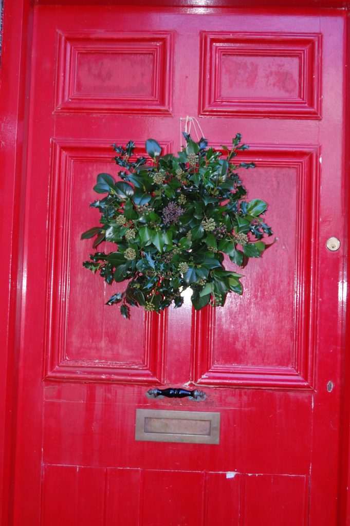 A red front door with a home made wreath