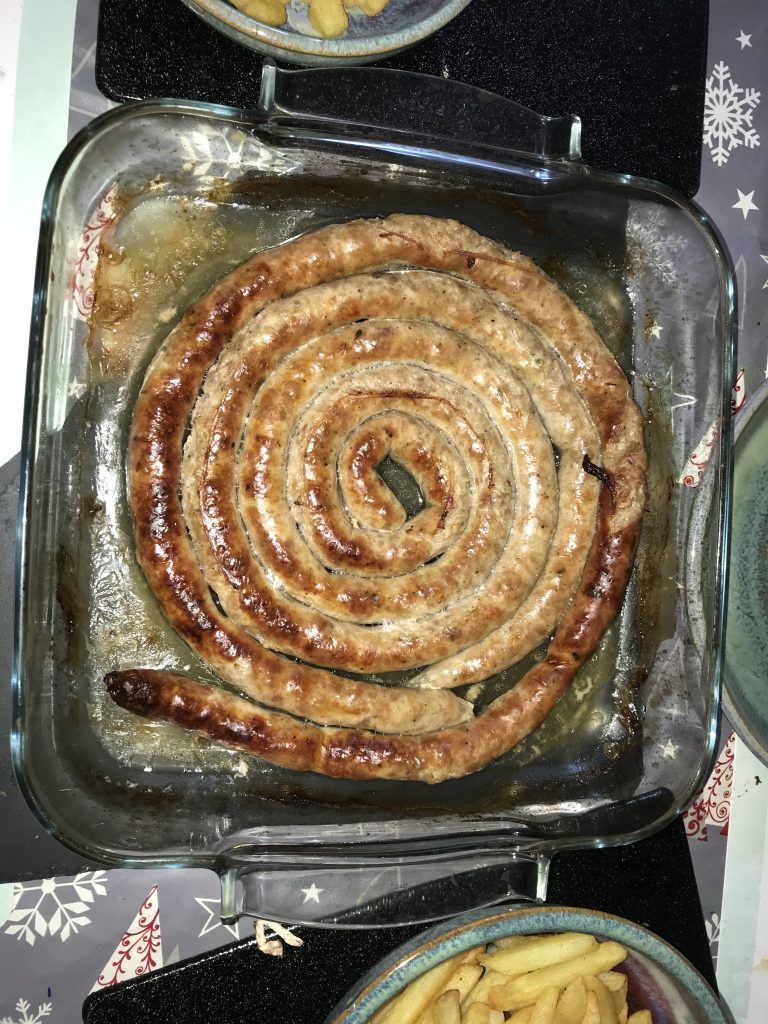 A dish with a cunberland like sausage curled in it.