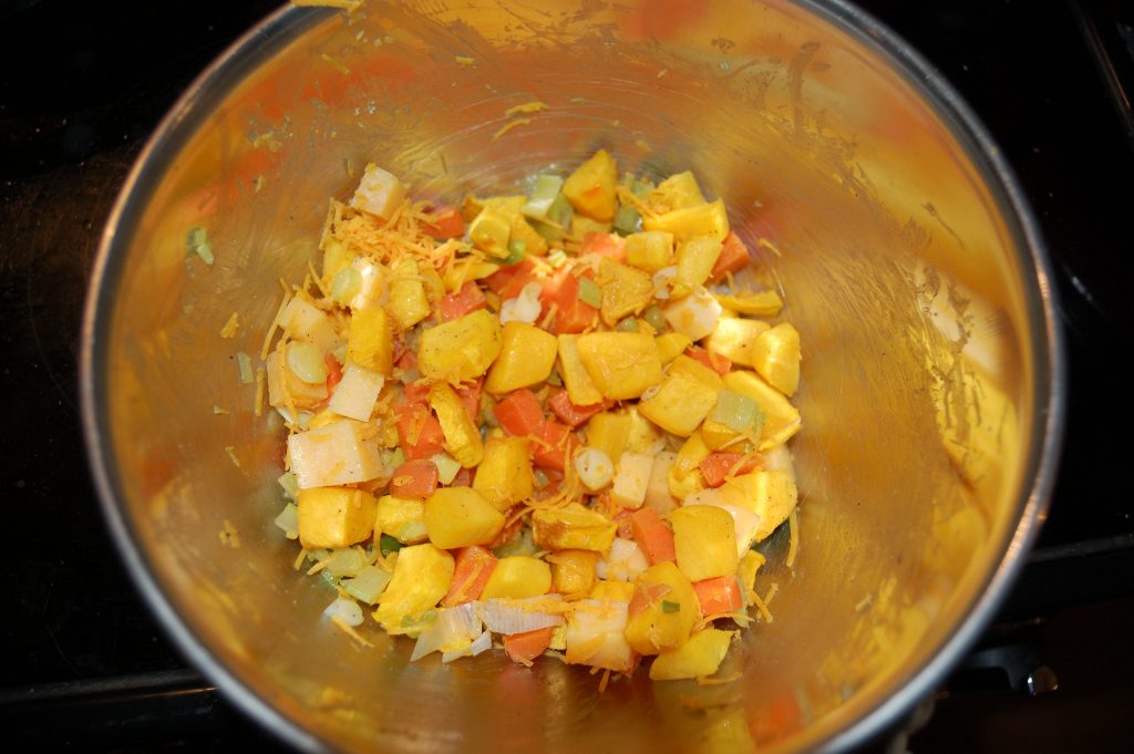 A mixing bowl with pumpkin, vegetables and grated cheese.