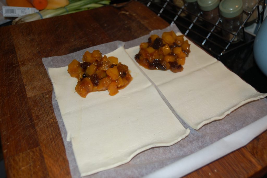 Two shets of pastry being filled with a sweet pumpkin filling