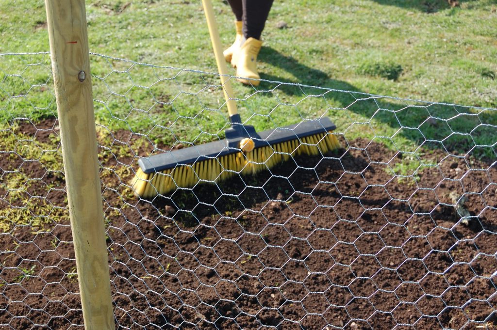 Brushing the last of the soil back onto the trench.